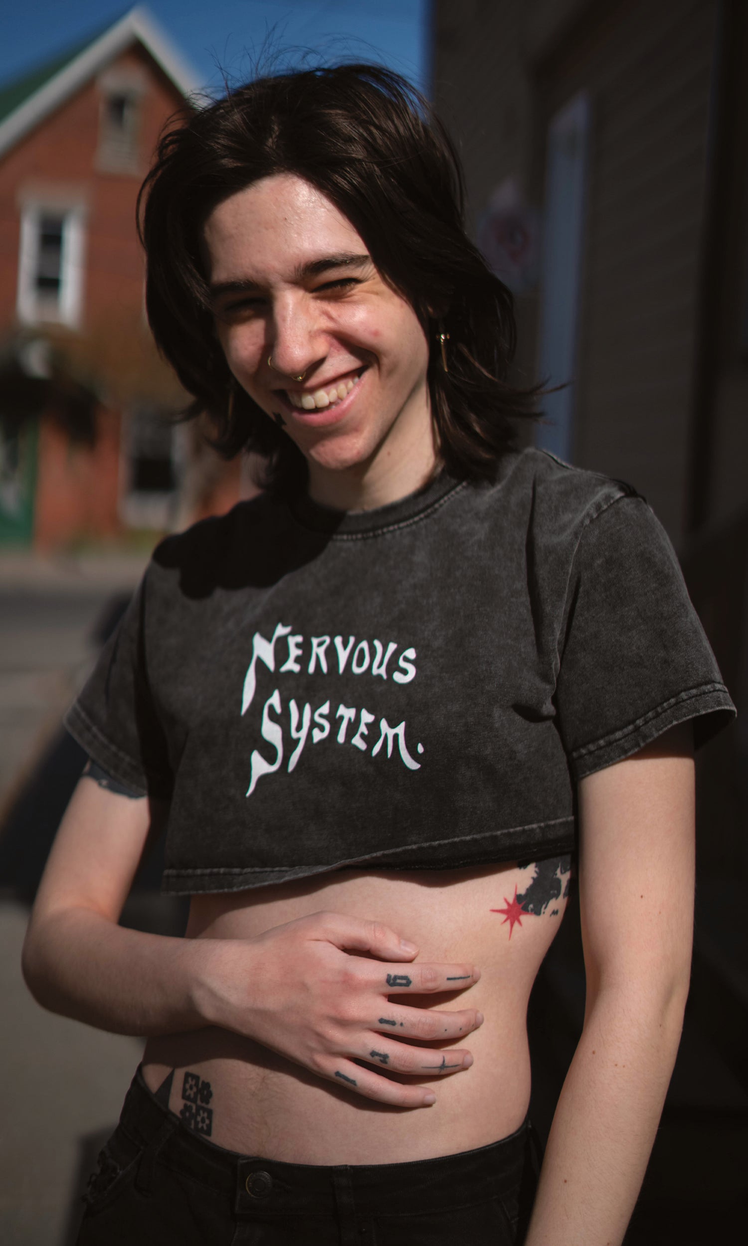 Person wearing a black t-shirt with 'Nervous System' text, standing outdoors.
