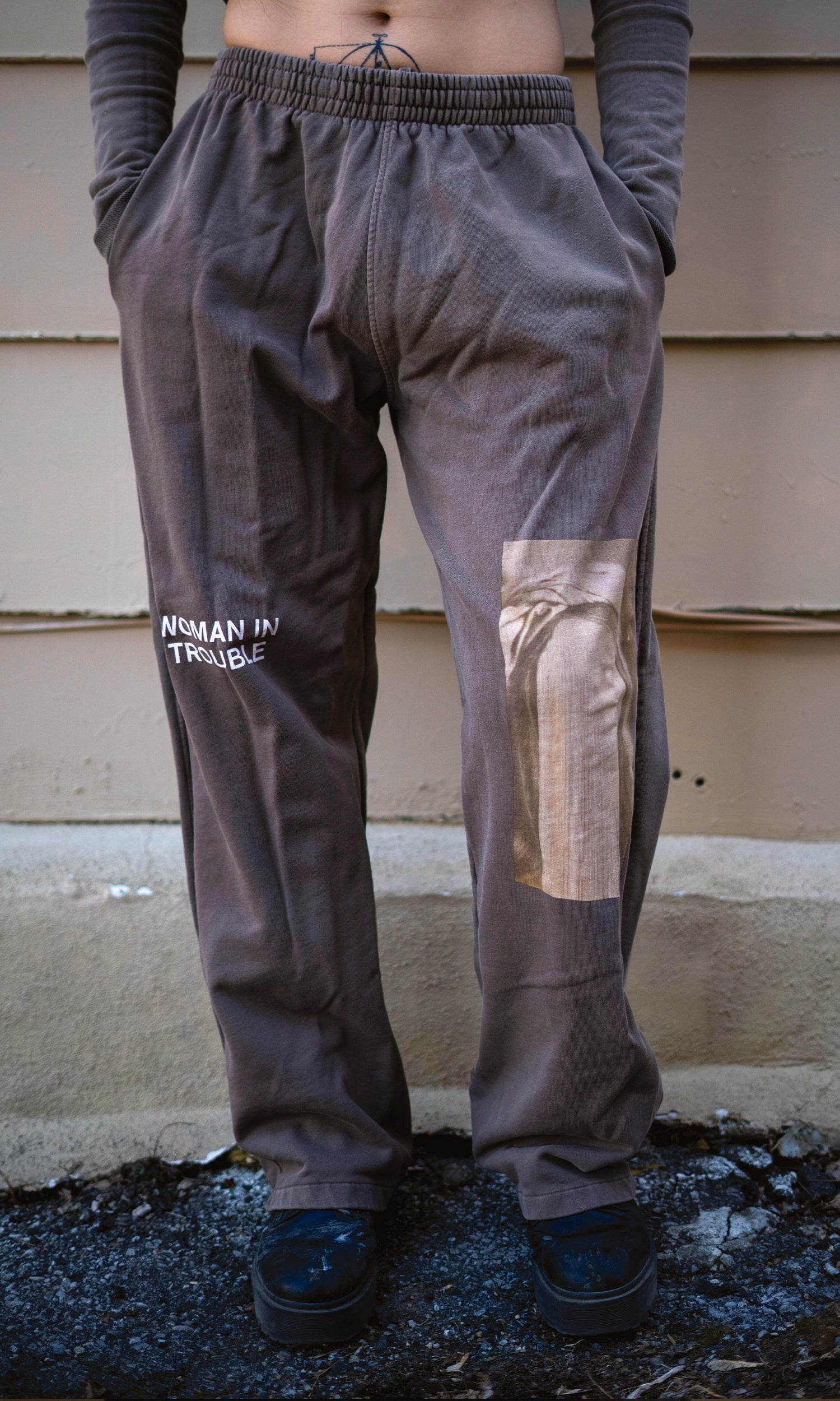 Person wearing tan sweatpants with a patch on a concrete surface