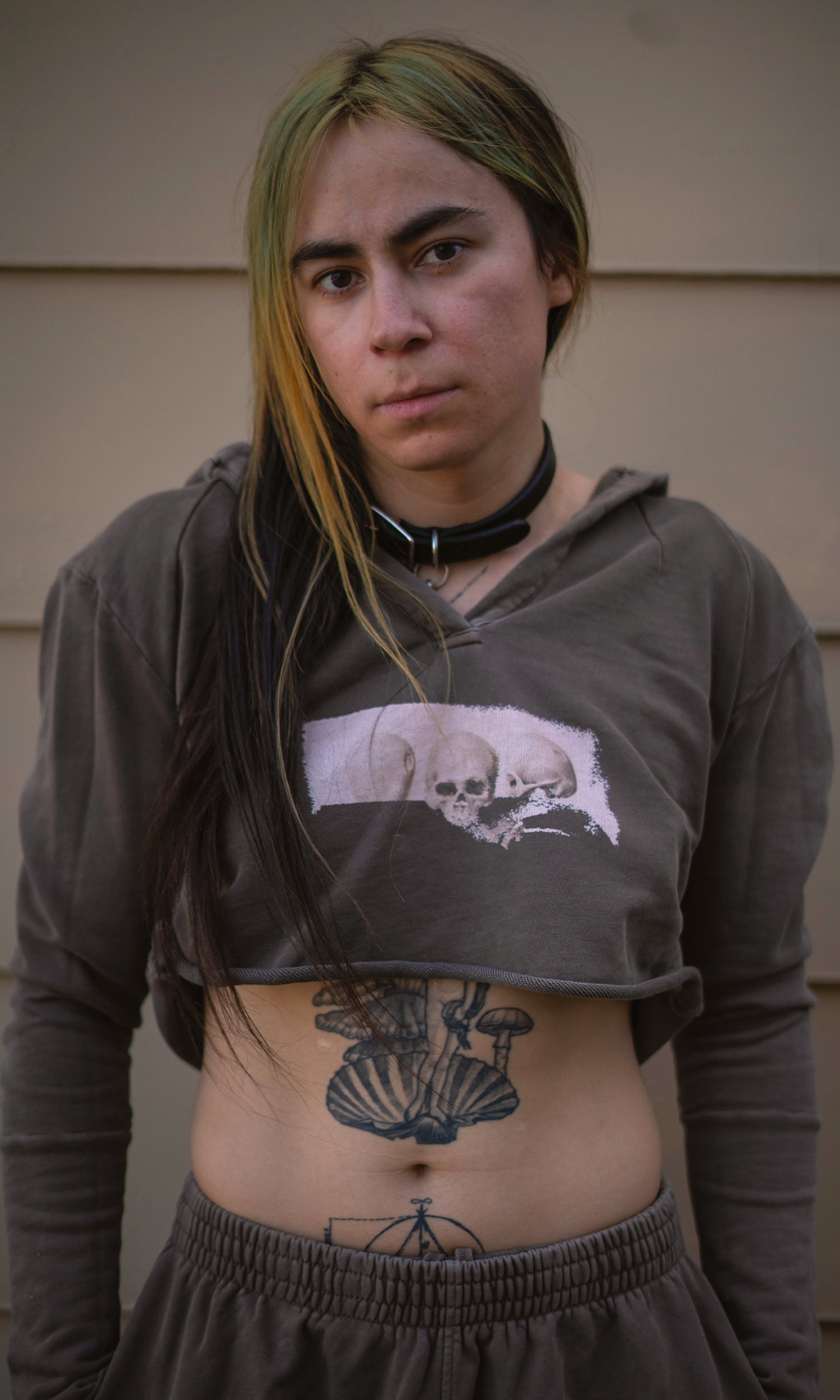 Person wearing a dark hoodie with a skull design, standing against a plain background