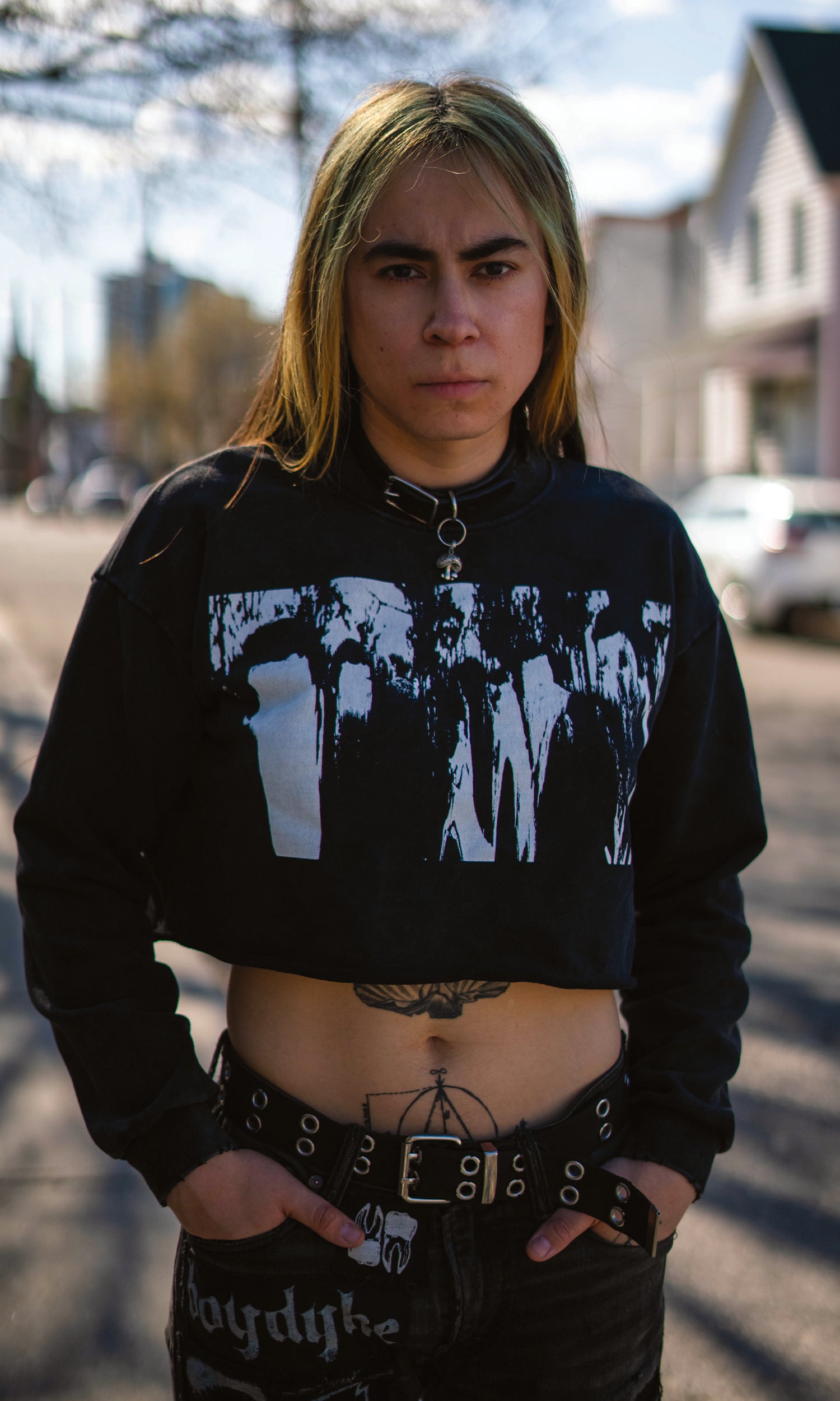 Person wearing a black hoodie with graphic design, standing on a street.